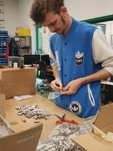 Le jeune Quentin prépare et emballe des pièces d'usinage sur son poste de travail